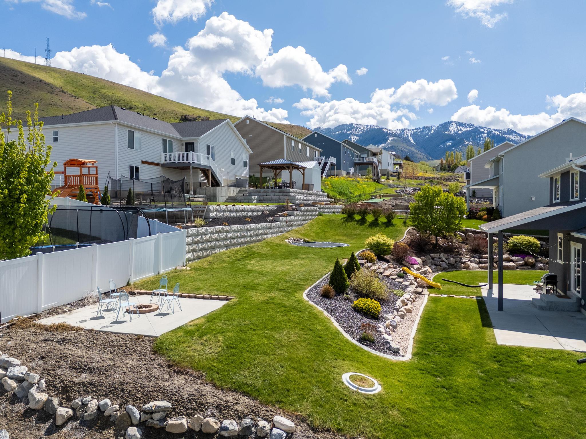 Fenced yard featuring a mountain view, a patio, a residential view, and an outdoor fire pit