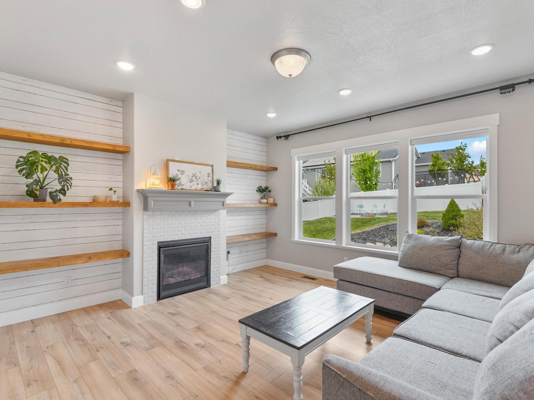 Living room featuring light wood finished floors, a glass covered fireplace, and recessed lighting