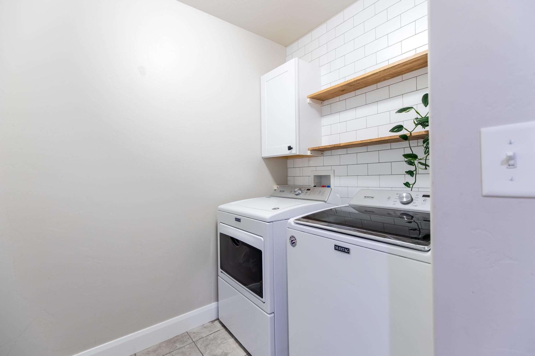 Laundry room with washer and clothes dryer, cabinet space, and light tile patterned floors