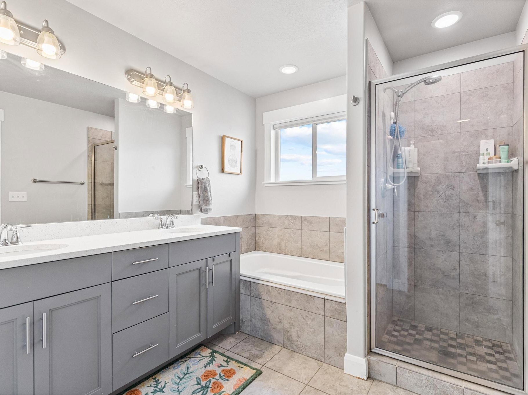 Full bath with double vanity, a garden tub, a stall shower, and light tile patterned floors