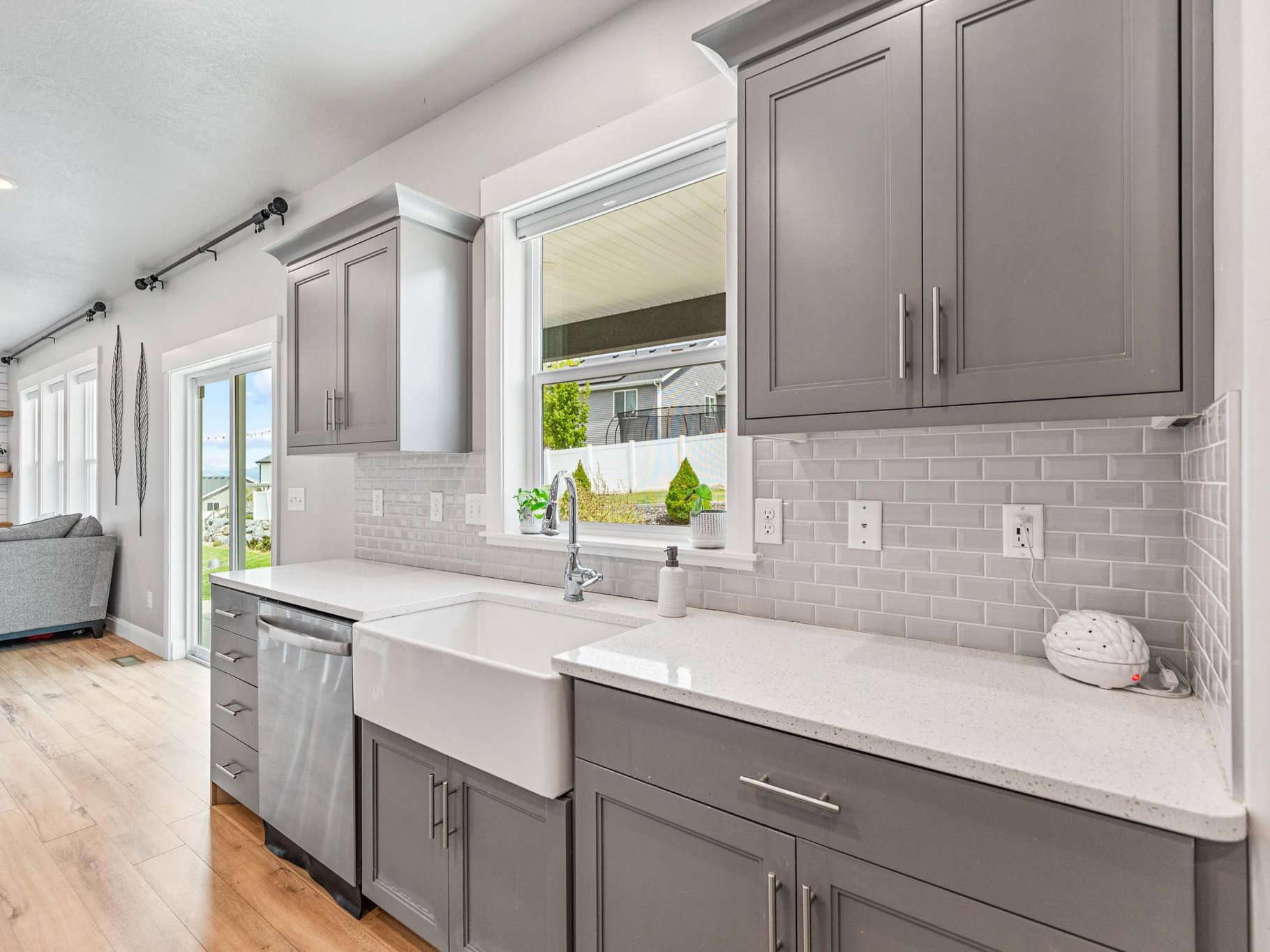 Kitchen featuring gray cabinets, light stone countertops, light wood-style floors, open floor plan, and dishwasher