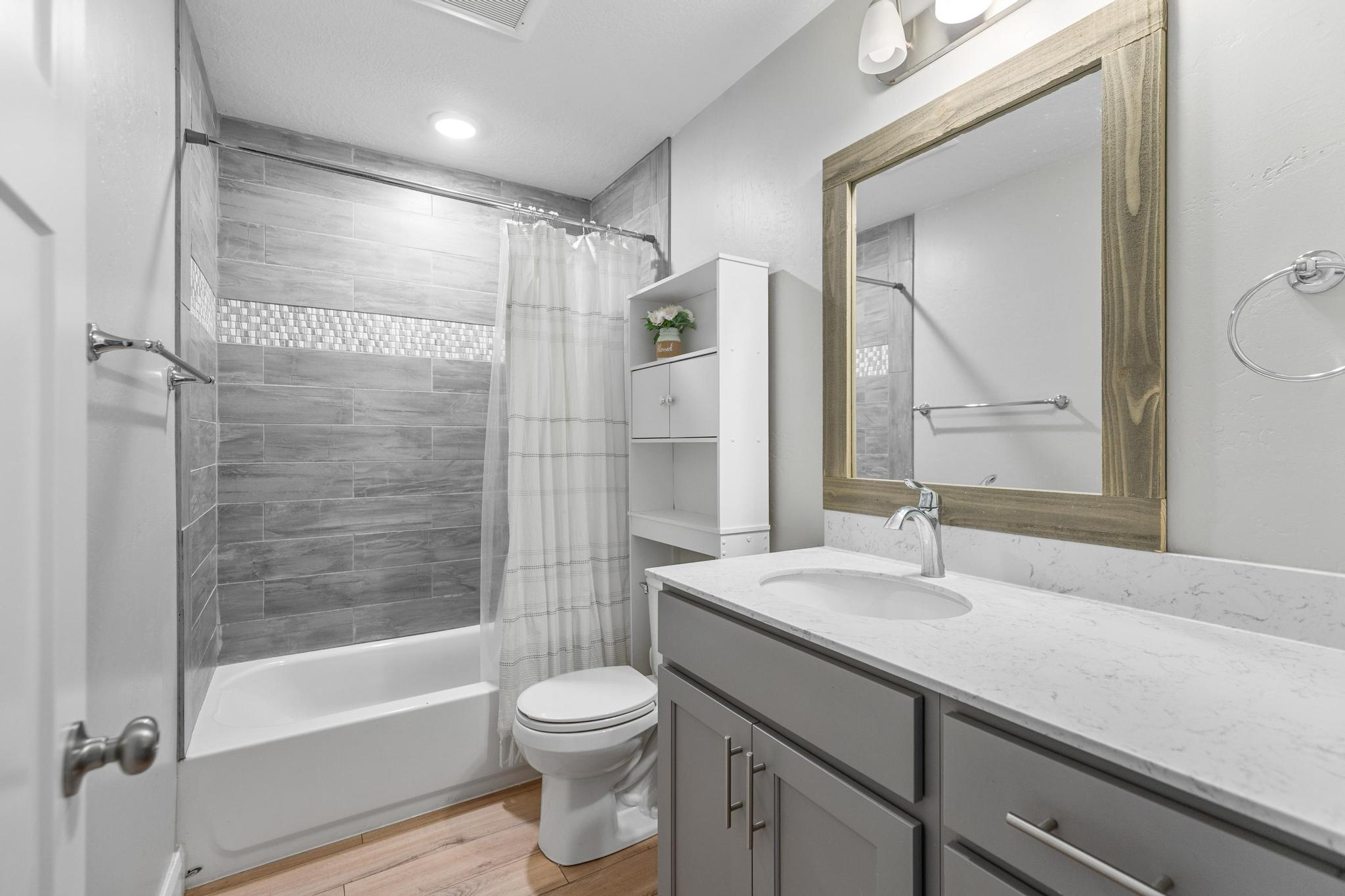 Full bathroom featuring vanity, shower / tub combo, and light wood-style floors