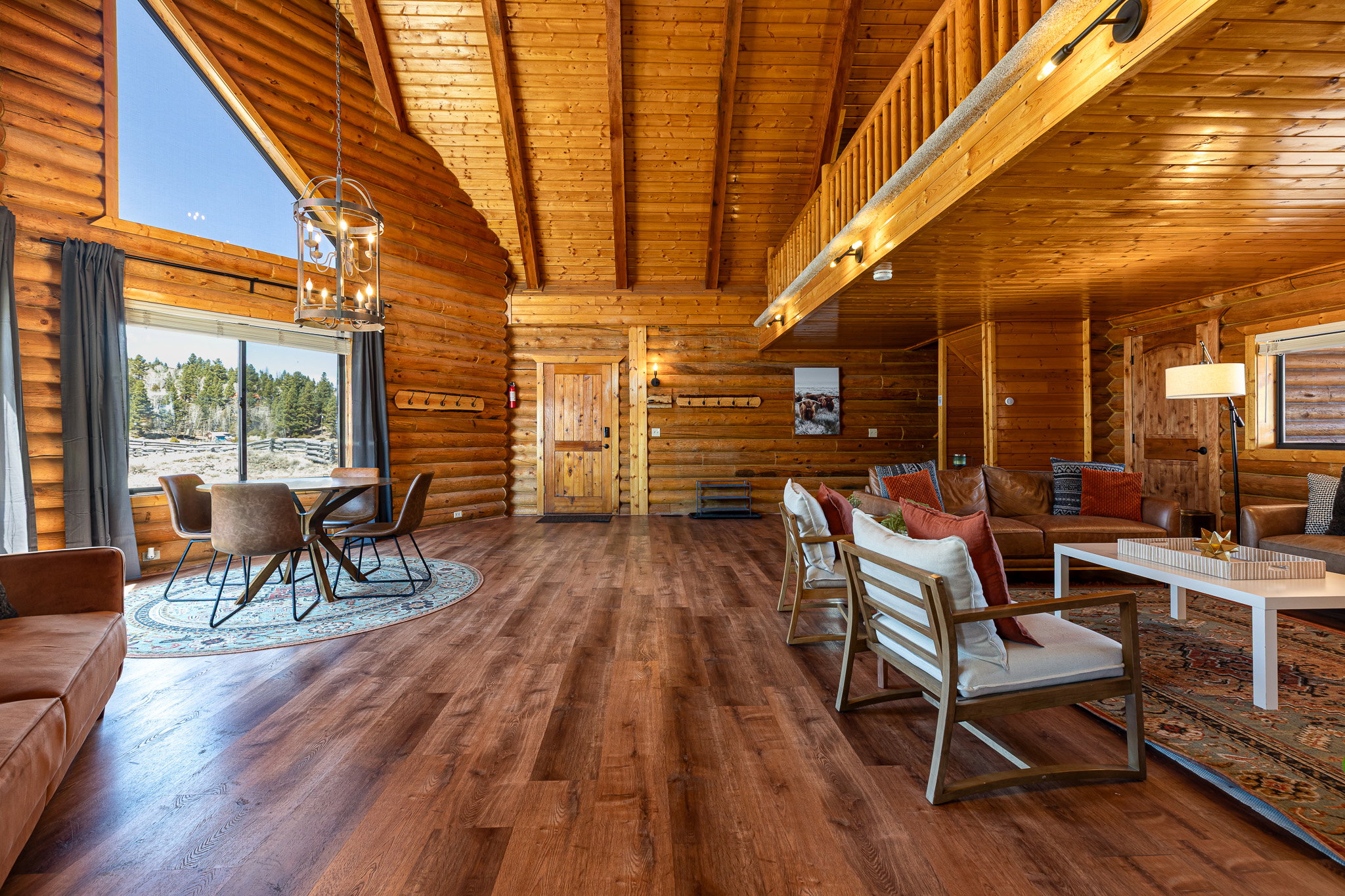 Living room with rustic walls, a high wood beamed ceiling, hanging lights, and dark wood finished floors