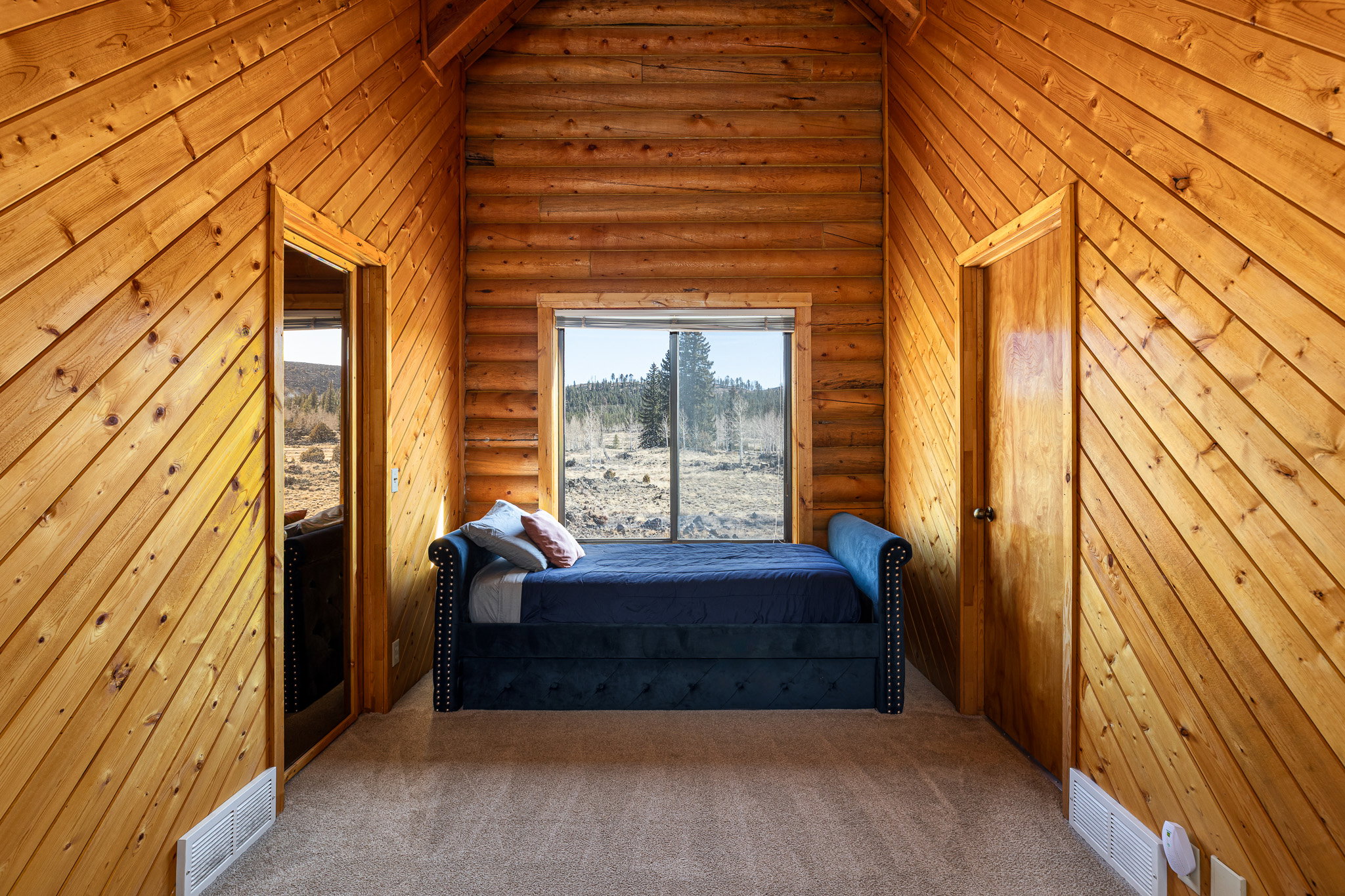 Carpeted bedroom with log walls and vaulted ceiling
