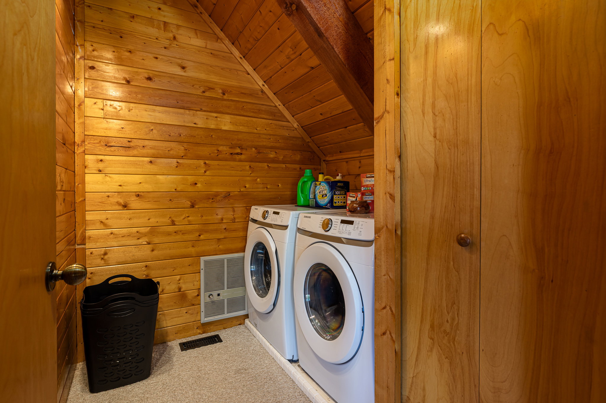 Laundry room featuring a vaulted wood ceiling, washing machine and dryer, wood walls, and light colored carpet