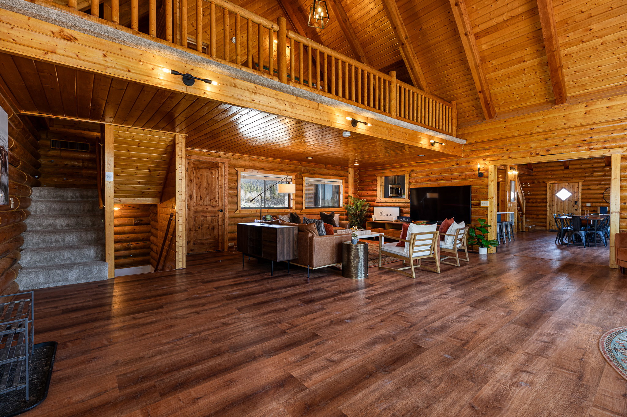 Living area with a high wood beamed ceiling, dark wood-style floors, and rustic walls
