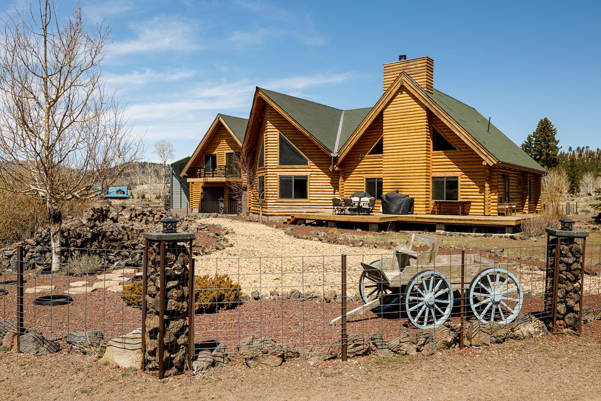 Back of house featuring log siding, a chimney, and roof with shingles