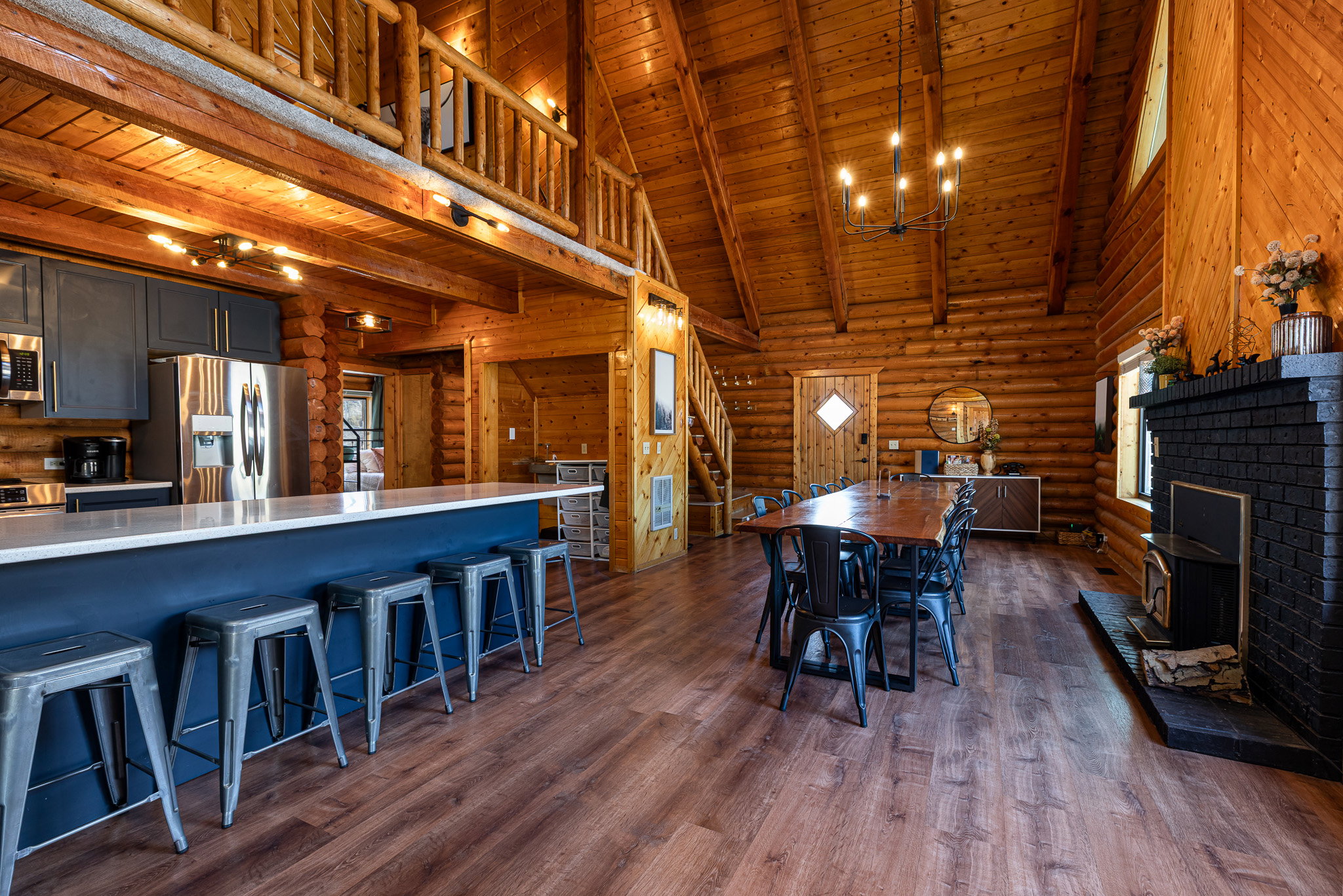 Dining area with rustic walls, a high wooden beamed ceiling, dark wood-style flooring, and hanging lights