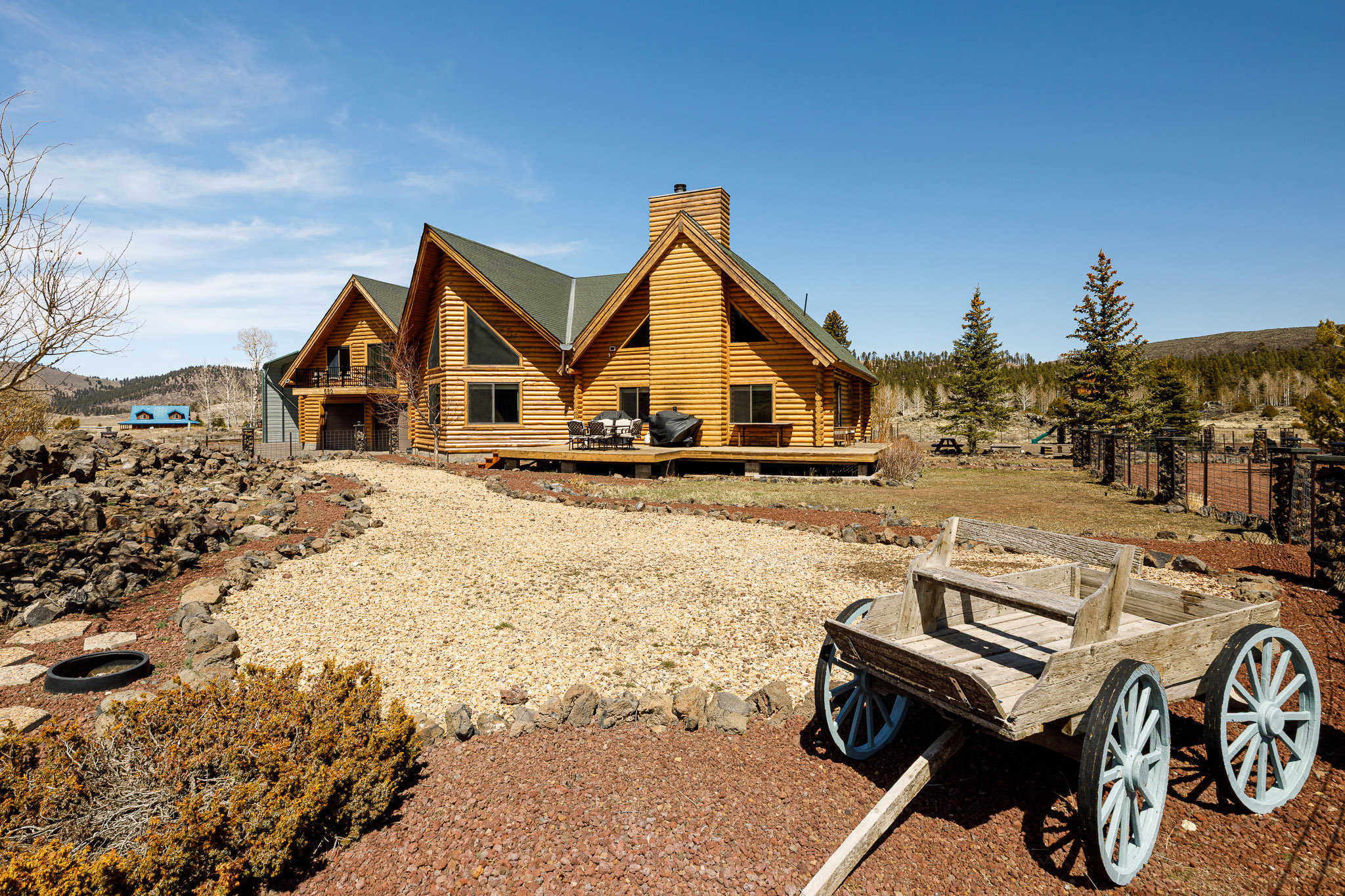 Back of house with a deck, a chimney, and log exterior