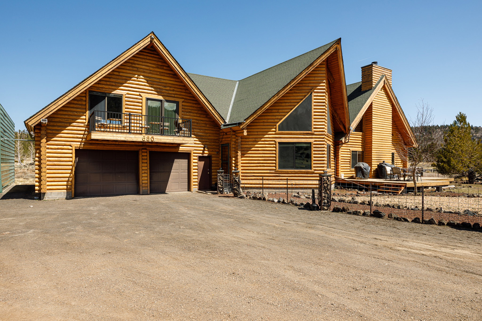 Log cabin with log exterior, a garage, driveway, and a chimney
