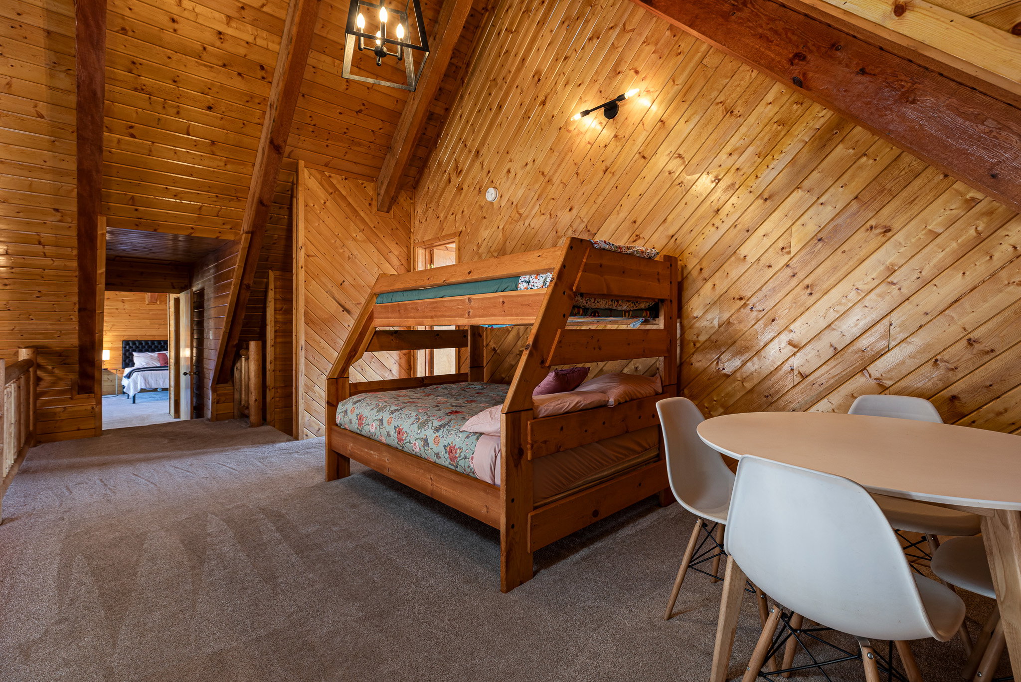 Carpeted bedroom with wood walls and a high wooden beamed ceiling