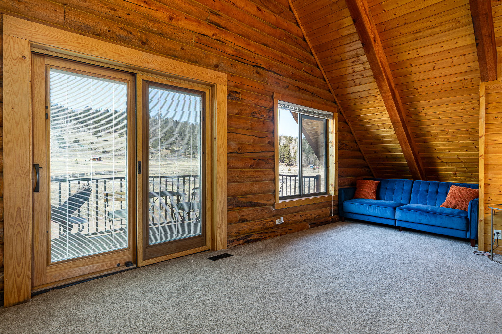 Unfurnished living room with wooden ceiling, carpet flooring, lofted ceiling with beams, and log walls