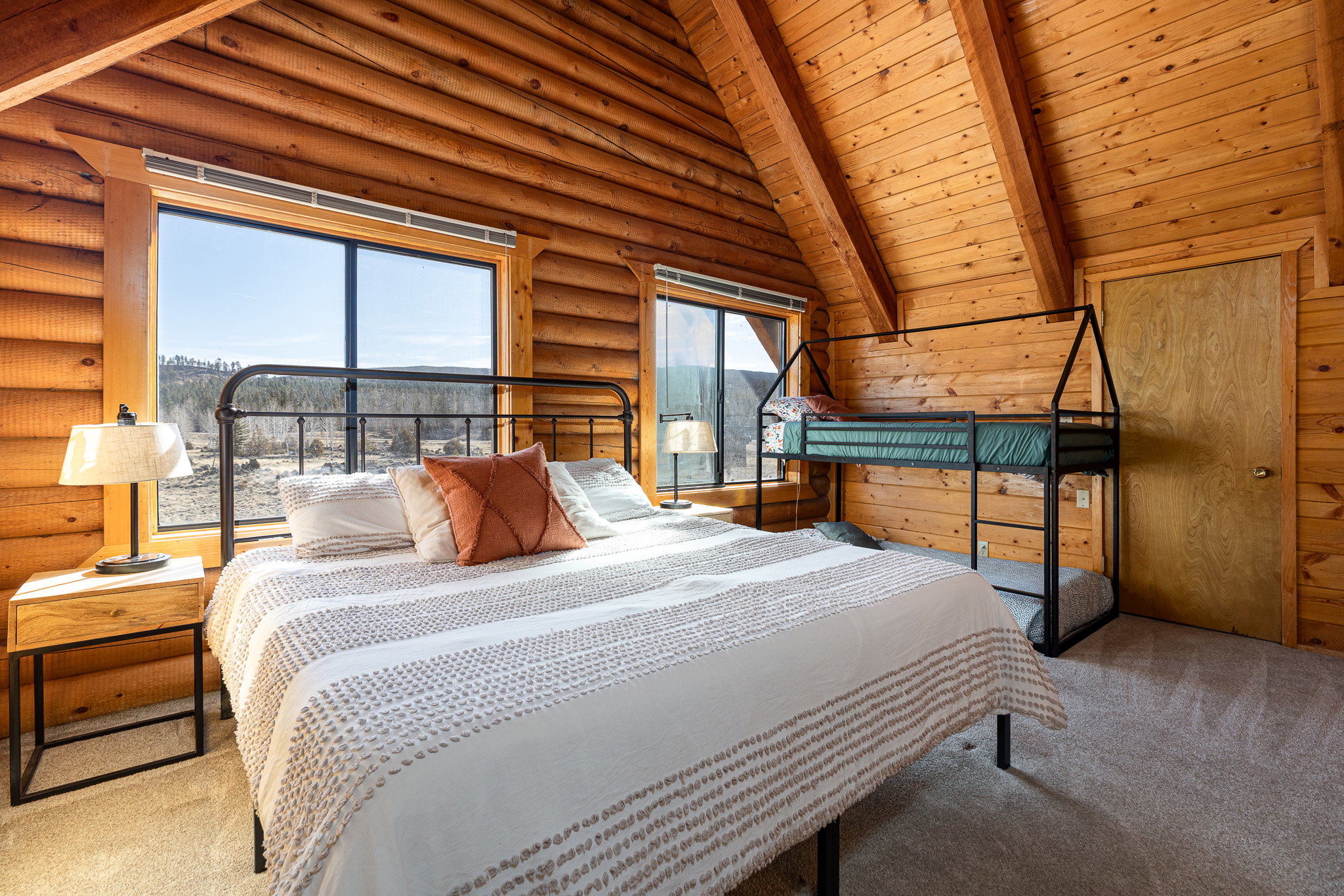 Carpeted bedroom with log walls, wooden ceiling, and vaulted ceiling with beams