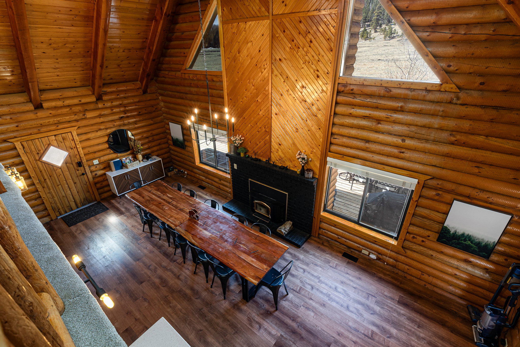 Dining area featuring rustic walls, dark wood-style floors, a wood stove, a high wooden beamed ceiling, and hanging lights