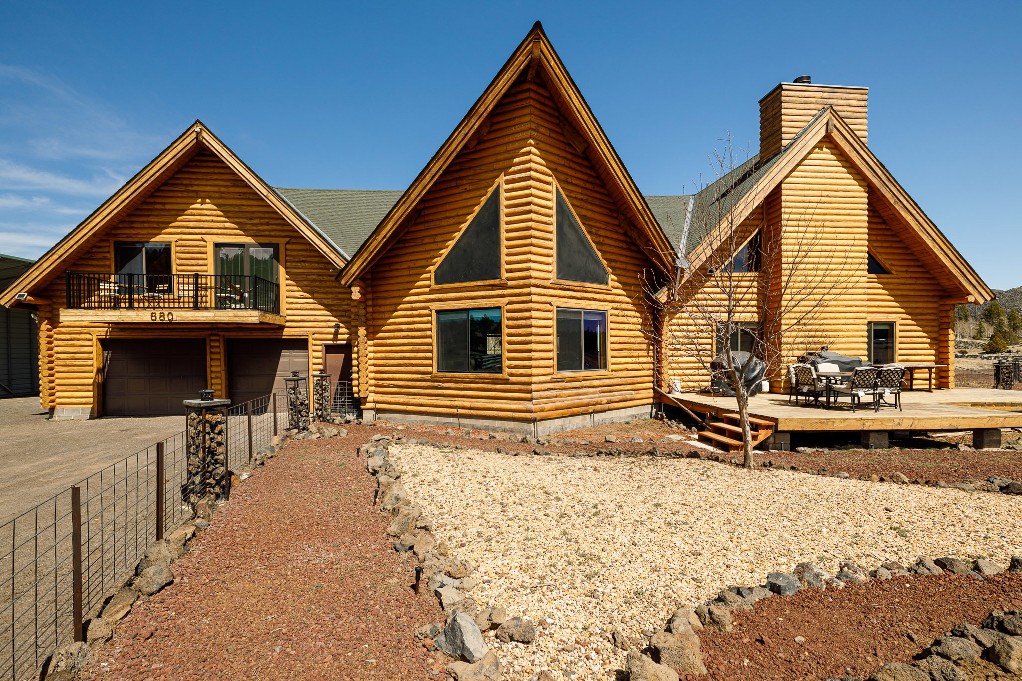 View of front facade with log siding, a garage, a chimney, and asphalt driveway
