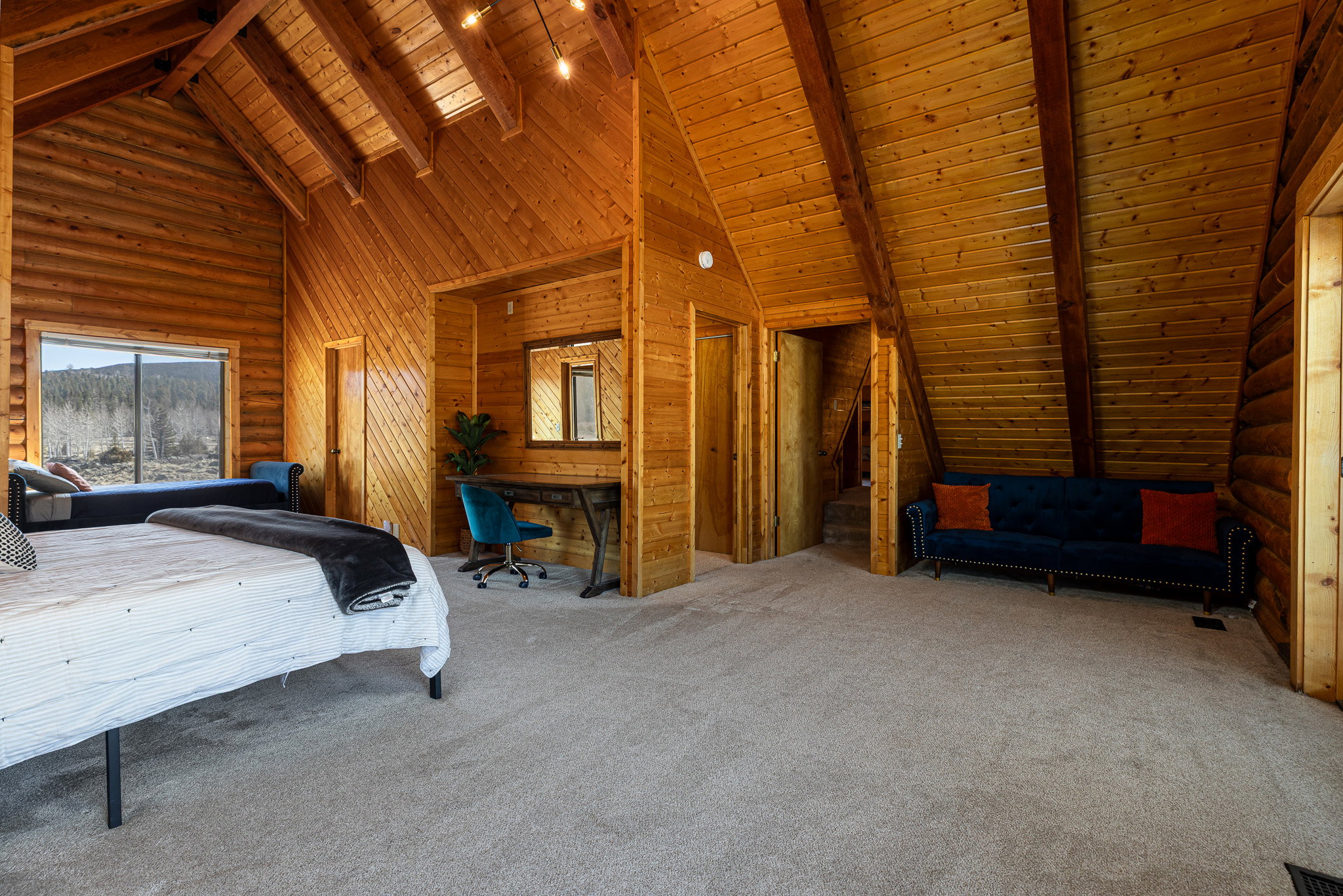 Carpeted bedroom with a high wooden beamed ceiling, rustic walls, and wooden walls