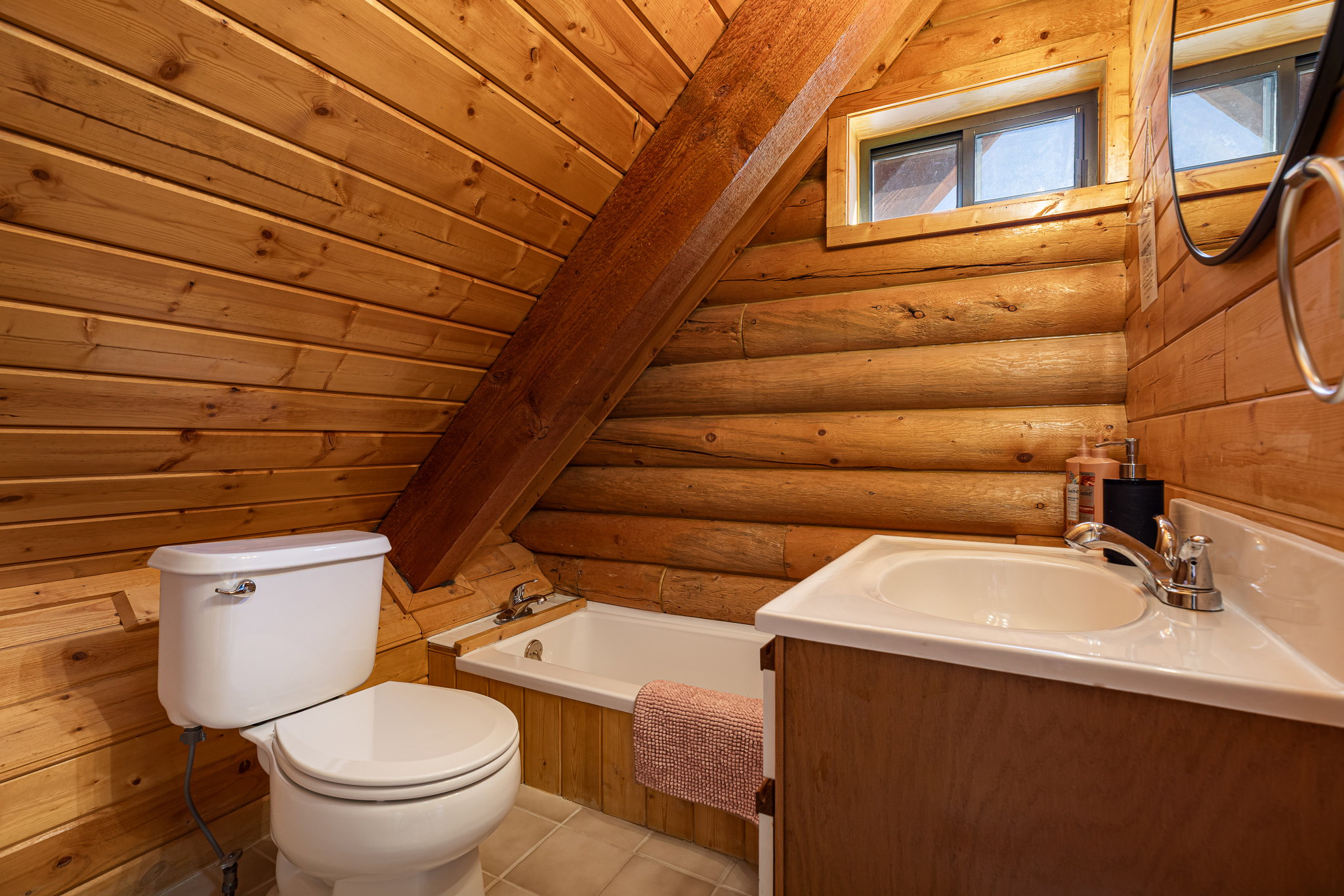 Bathroom featuring vanity, log walls, a tub to relax in, a vaulted wooden ceiling, and light tile patterned floors