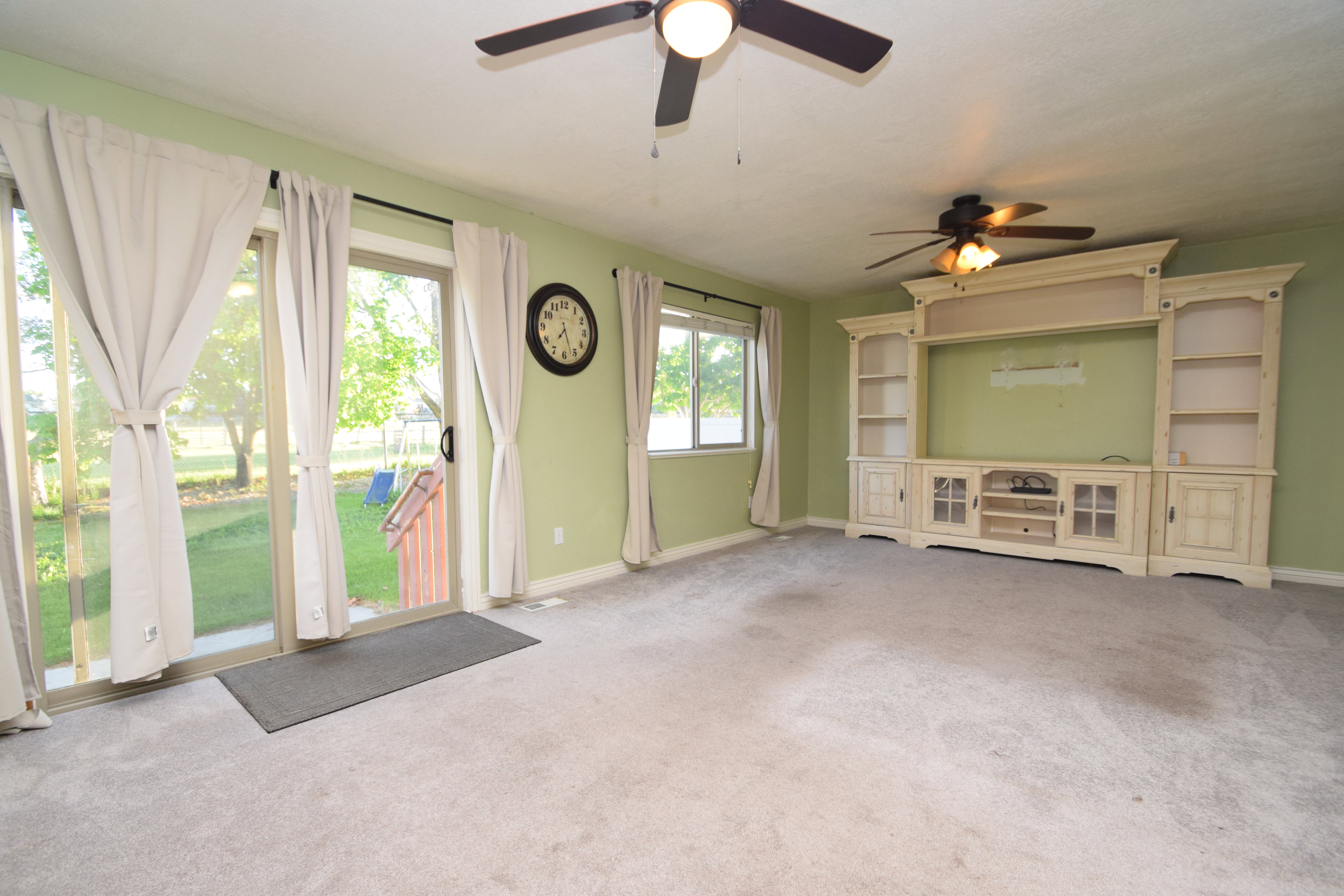 Unfurnished living room featuring carpet and a ceiling fan
