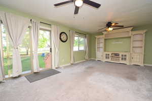 Unfurnished living room featuring carpet and a ceiling fan