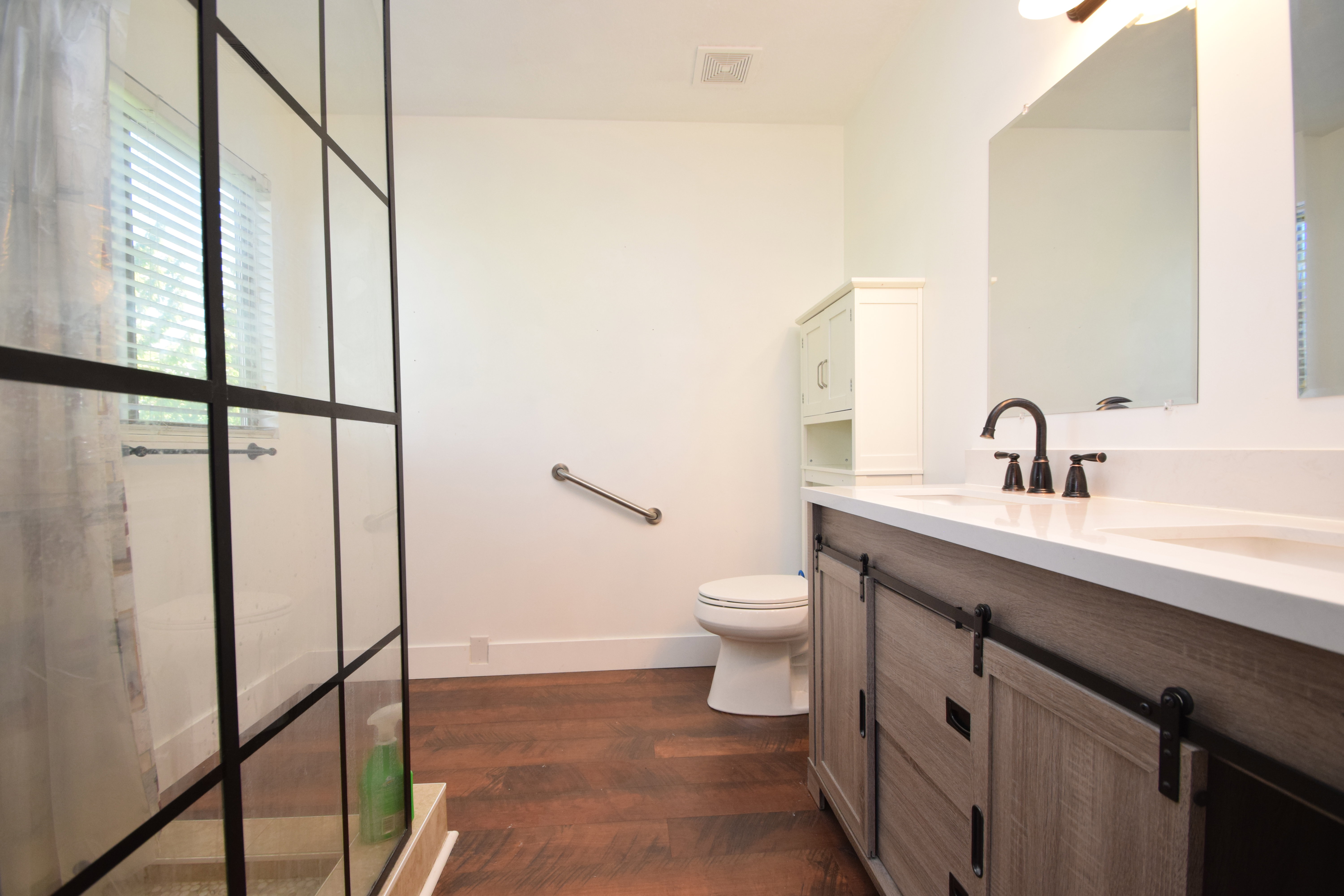 Bathroom with double vanity and dark wood-style floors