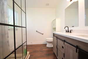 Bathroom with double vanity and dark wood-style floors
