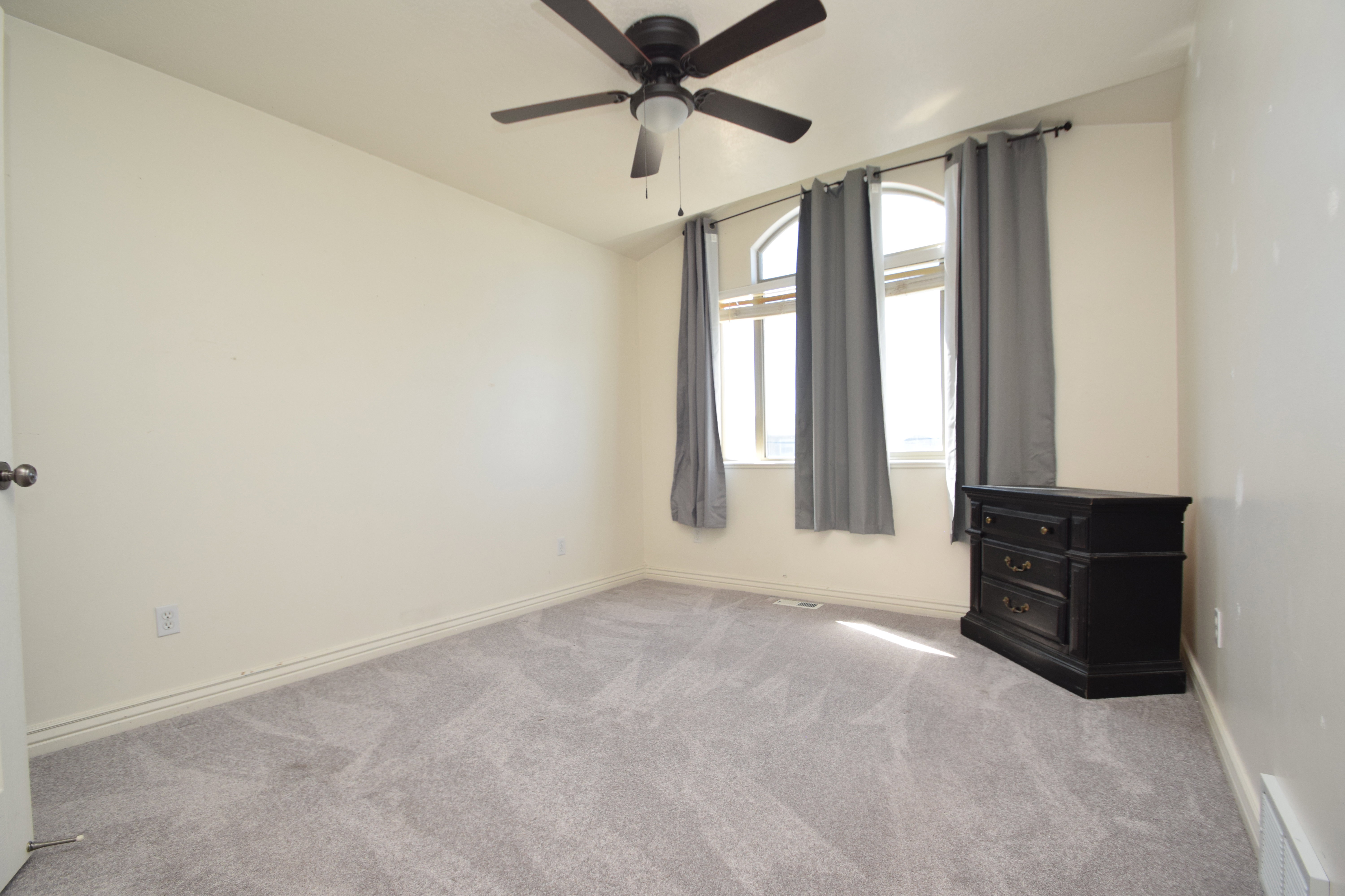 Empty room with light carpet, lofted ceiling, and ceiling fan