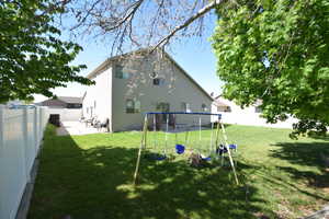 Back of house with a playground and a fenced backyard