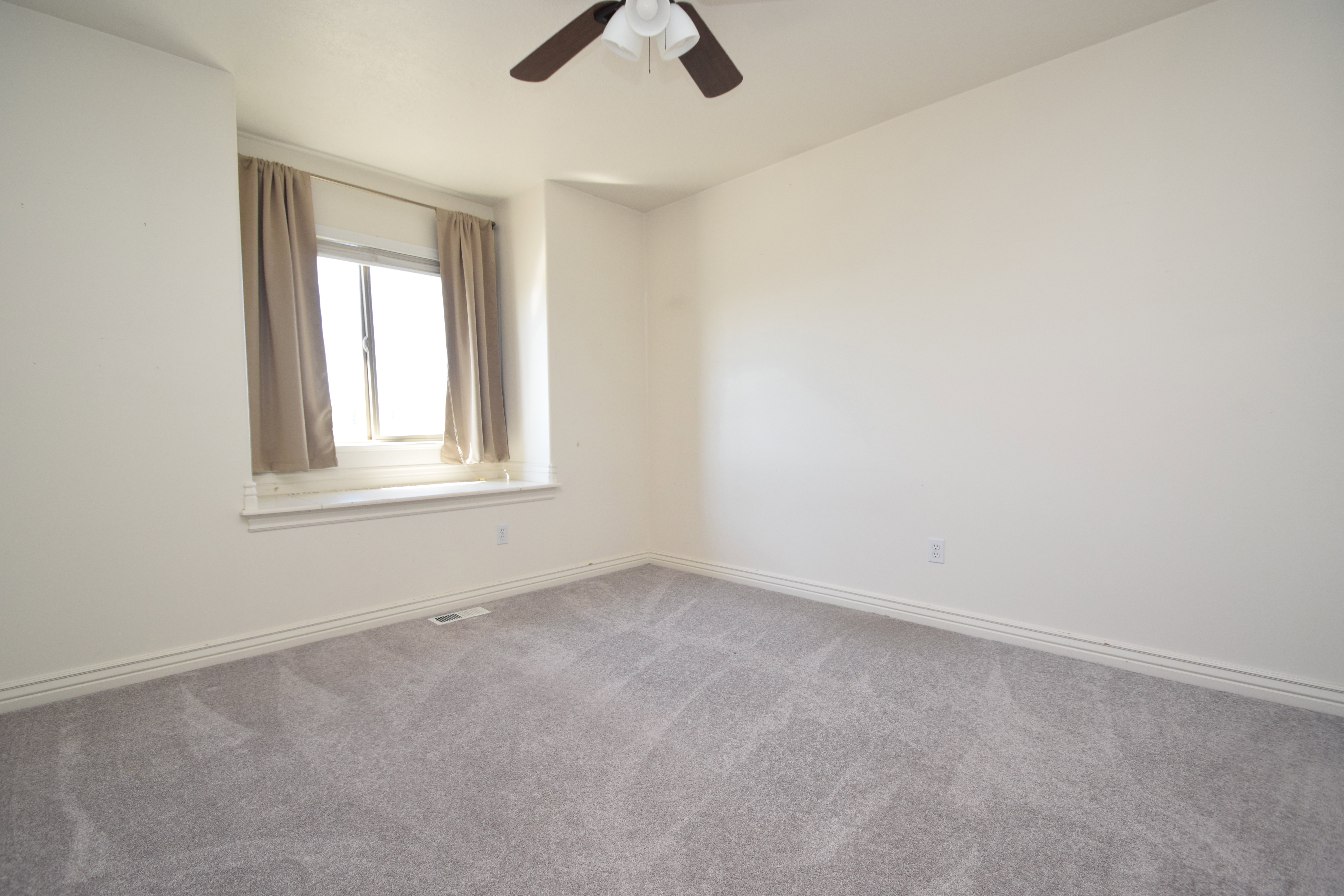 Carpeted spare room featuring baseboards and ceiling fan