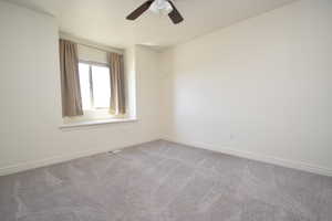 Carpeted spare room featuring baseboards and ceiling fan