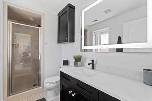 Bathroom featuring a stall shower, vanity, and light tile patterned floors