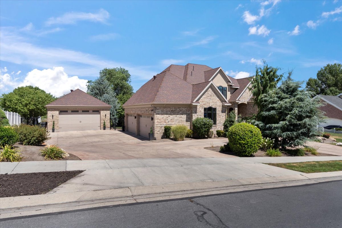 View of front of house featuring brick siding, roof with shingles, concrete driveway, stone siding, and a garage