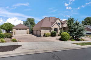 View of front of house featuring brick siding, roof with shingles, concrete driveway, stone siding, and a garage