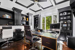 Home office with coffered ceiling, dark wood finished floors, a ceiling fan, and ornamental molding