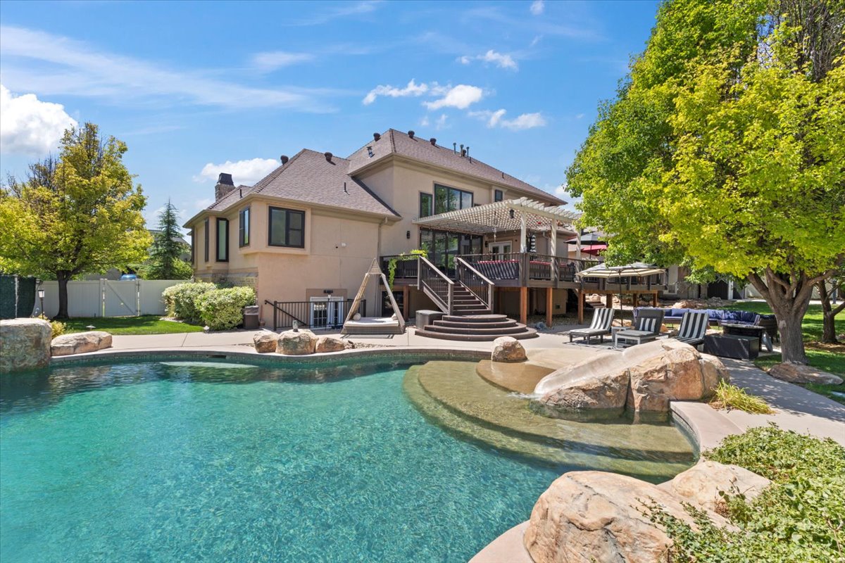 Back of property featuring a patio, a chimney, stucco siding, a pergola, and a gate
