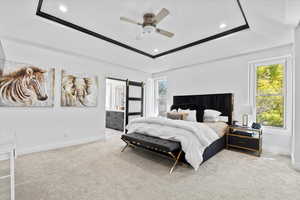Bedroom with light colored carpet, ceiling fan, recessed lighting, a raised ceiling, and connected bathroom