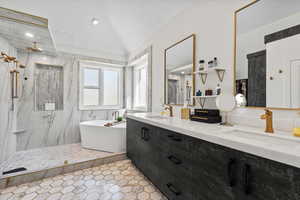 Full bathroom with double vanity, a freestanding bath, a marble finish shower, and vaulted ceiling