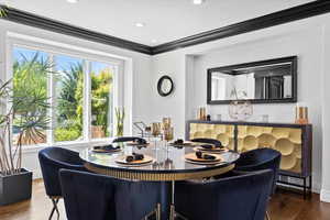 Dining area with dark wood finished floors, crown molding, and recessed lighting