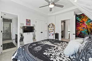 Bedroom with light colored carpet, a closet, ceiling fan, and ensuite bathroom