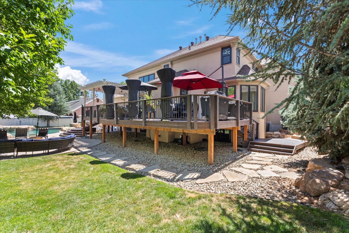 Back of house with a wooden deck, an outdoor lounge area, a yard, and stucco siding