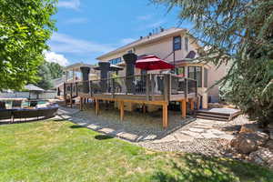Back of house with a wooden deck, an outdoor lounge area, a yard, and stucco siding