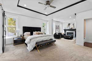 Carpeted bedroom featuring a glass covered fireplace, recessed lighting, multiple windows, a ceiling fan, and a barn door