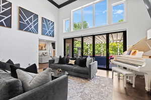 Living room with wood finished floors, crown molding, a high ceiling, and french doors