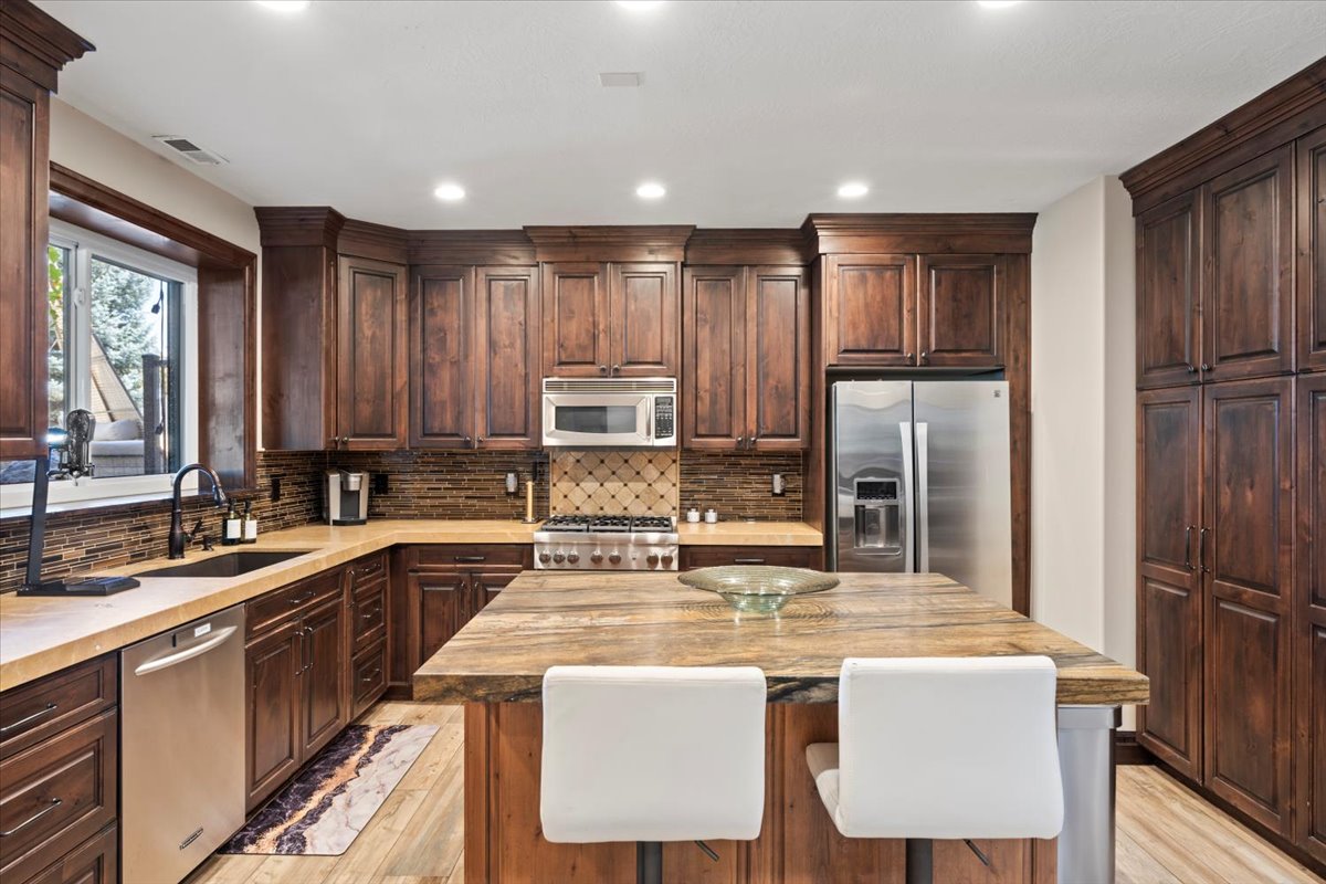 Kitchen with dark wood finish cabinets, stainless steel appliances, light wood-type flooring, and recessed lighting