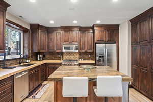 Kitchen with dark wood finish cabinets, stainless steel appliances, light wood-type flooring, and recessed lighting