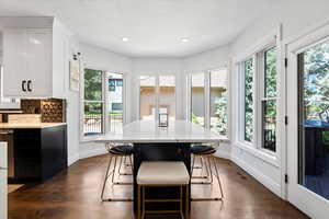 Kitchen with dual tone cabinets, light stone counters, a center island, a kitchen breakfast bar, and tasteful backsplash
