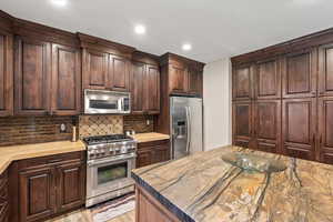 Kitchen featuring stainless steel appliances, dark wood finish cabinetry, tasteful backsplash, light wood-type flooring, and recessed lighting