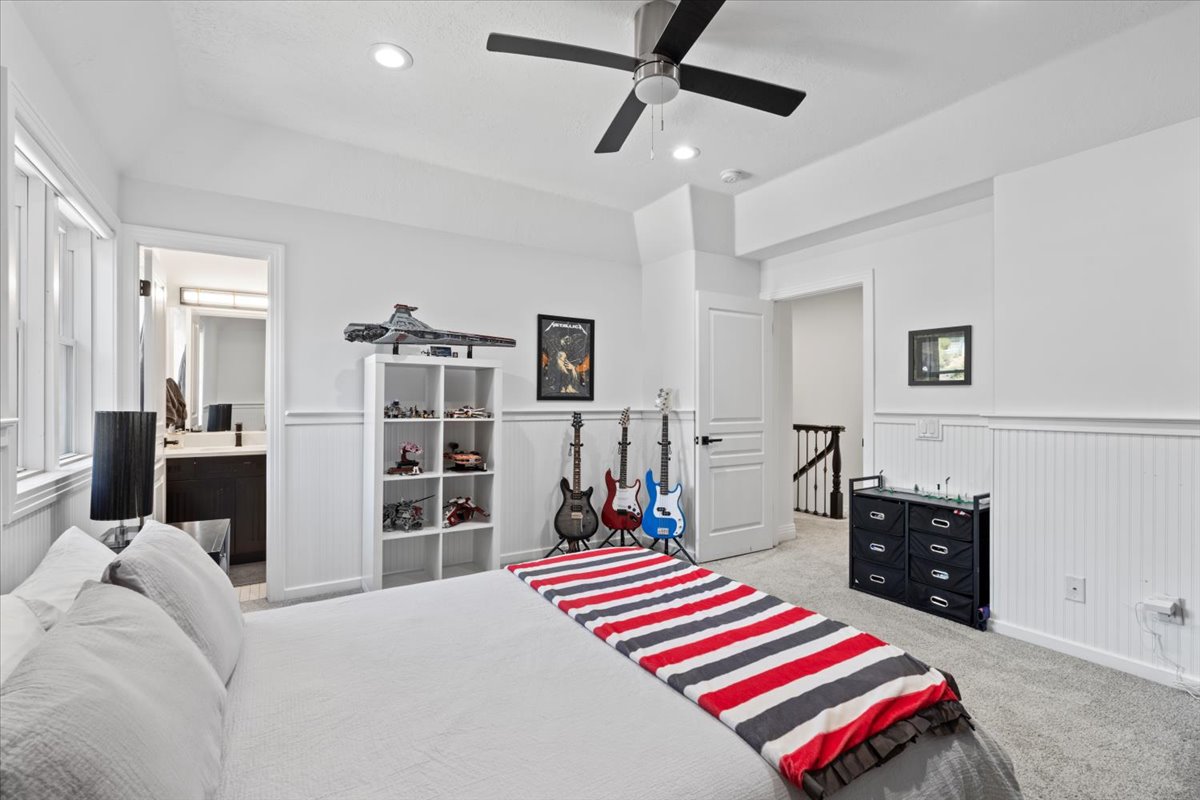 Bedroom featuring a wainscoted wall, a ceiling fan, light carpet, recessed lighting, and ensuite bath