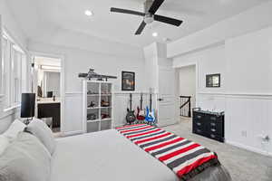 Bedroom featuring a wainscoted wall, a ceiling fan, light carpet, recessed lighting, and ensuite bath