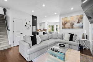 Living room with dark wood-type flooring, recessed lighting, and a textured ceiling