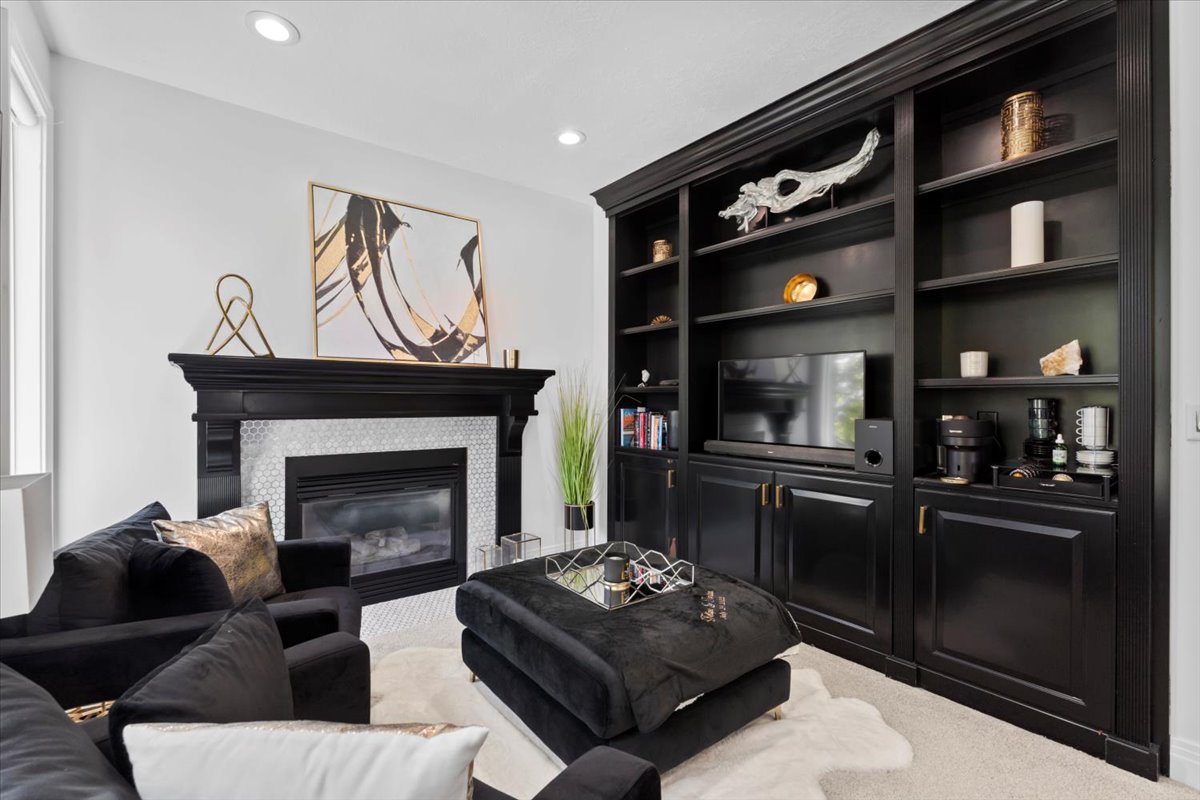 Carpeted living area with a tile fireplace, recessed lighting, and built in features